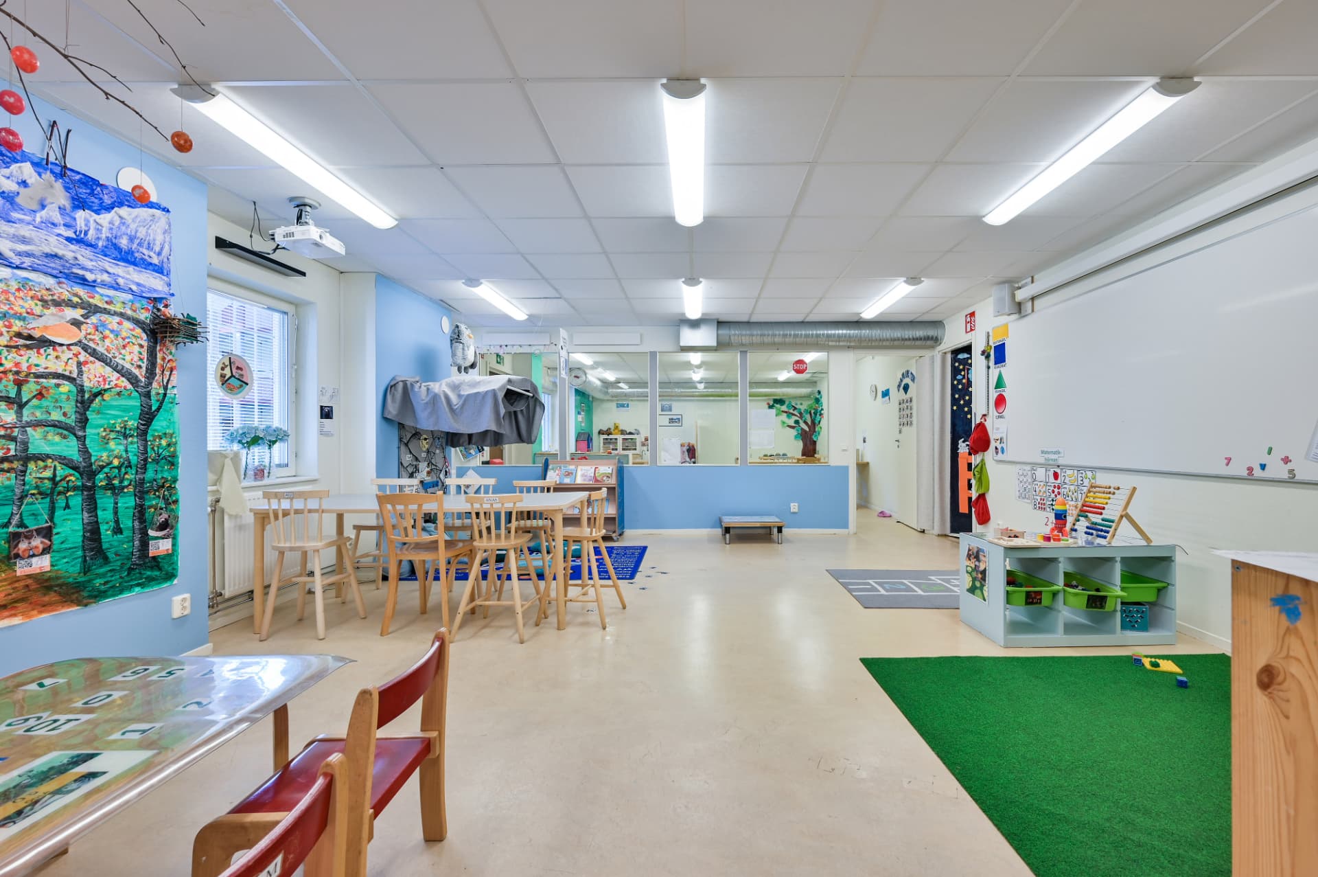 Ljus avdelning med matbord, barnens konstverk på väggen och en matematikhörna